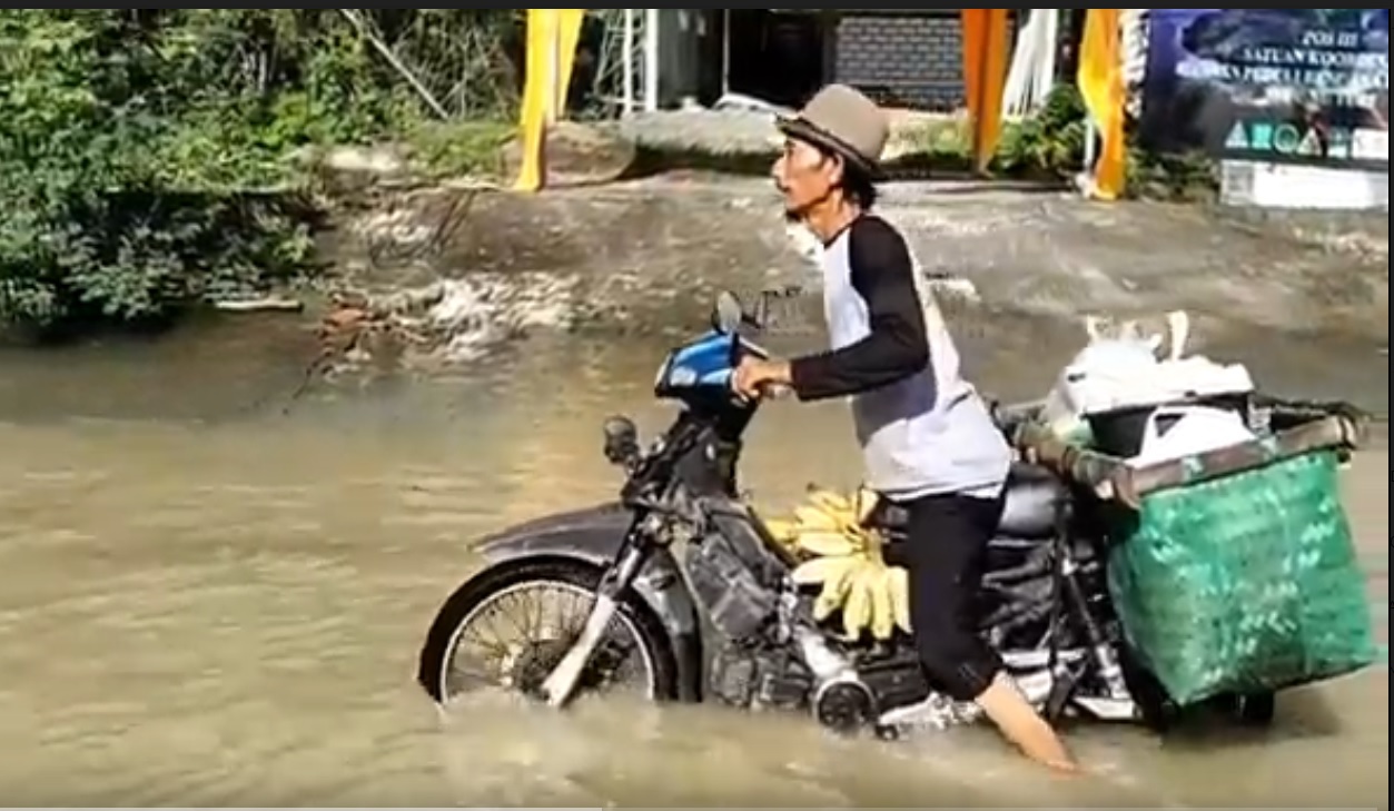 Warga harus  mendorong motor saat melintas jalan utama di Kecamatan Turi, Lamongan. (metrotv) 