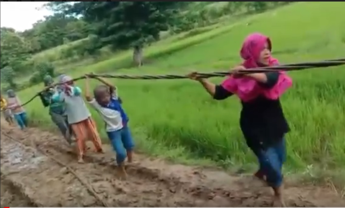 Ibu-ibu dari Desa Kolo-kolo, Kepulauan Kangean, Sumenep mengangkat kabel melewati jalan berlumpur. (metrotv)