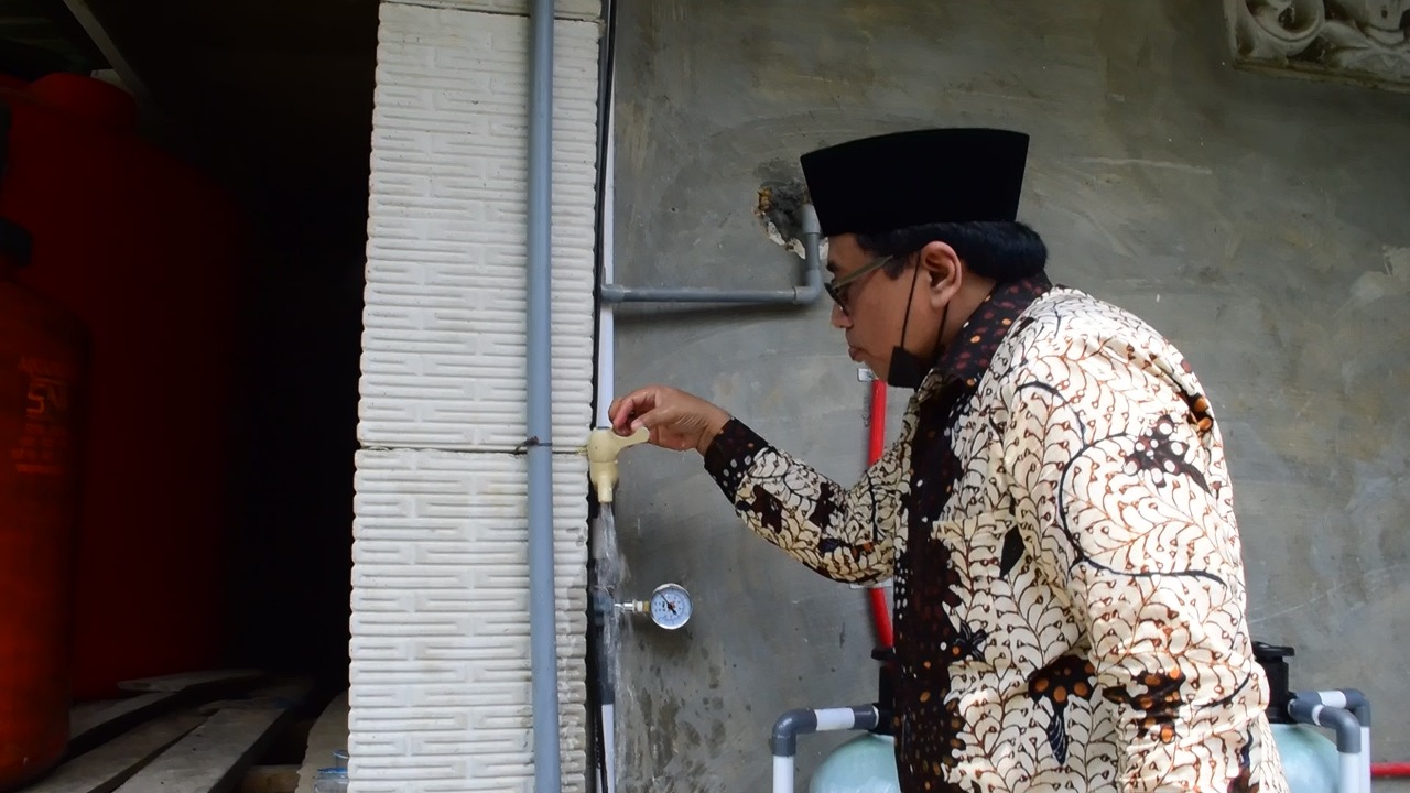 Anggota DPRD Pamekasan, M. Lutfi, sedang mencoba air dari hasil instalasi air bersih yang dibuat oleh Unusa (Foto / Hum)