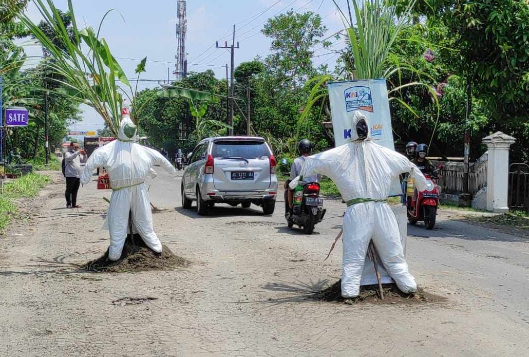 Boneka nakes mengenakan hazmat dipasang di tengah jalan sebagai bentuk protes warga akibat jalan rusak (Foto / Metro TV)