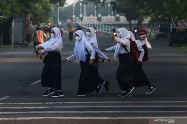 Foto Arsip - Sejumlah pelajar menyeberang jalan menuju ke sekolah di kawasan Platuk Donomulyo, Surabaya, Jawa Timur, Senin (10/1/2022). (Antara Jatim/Didik Suhartono/zk)