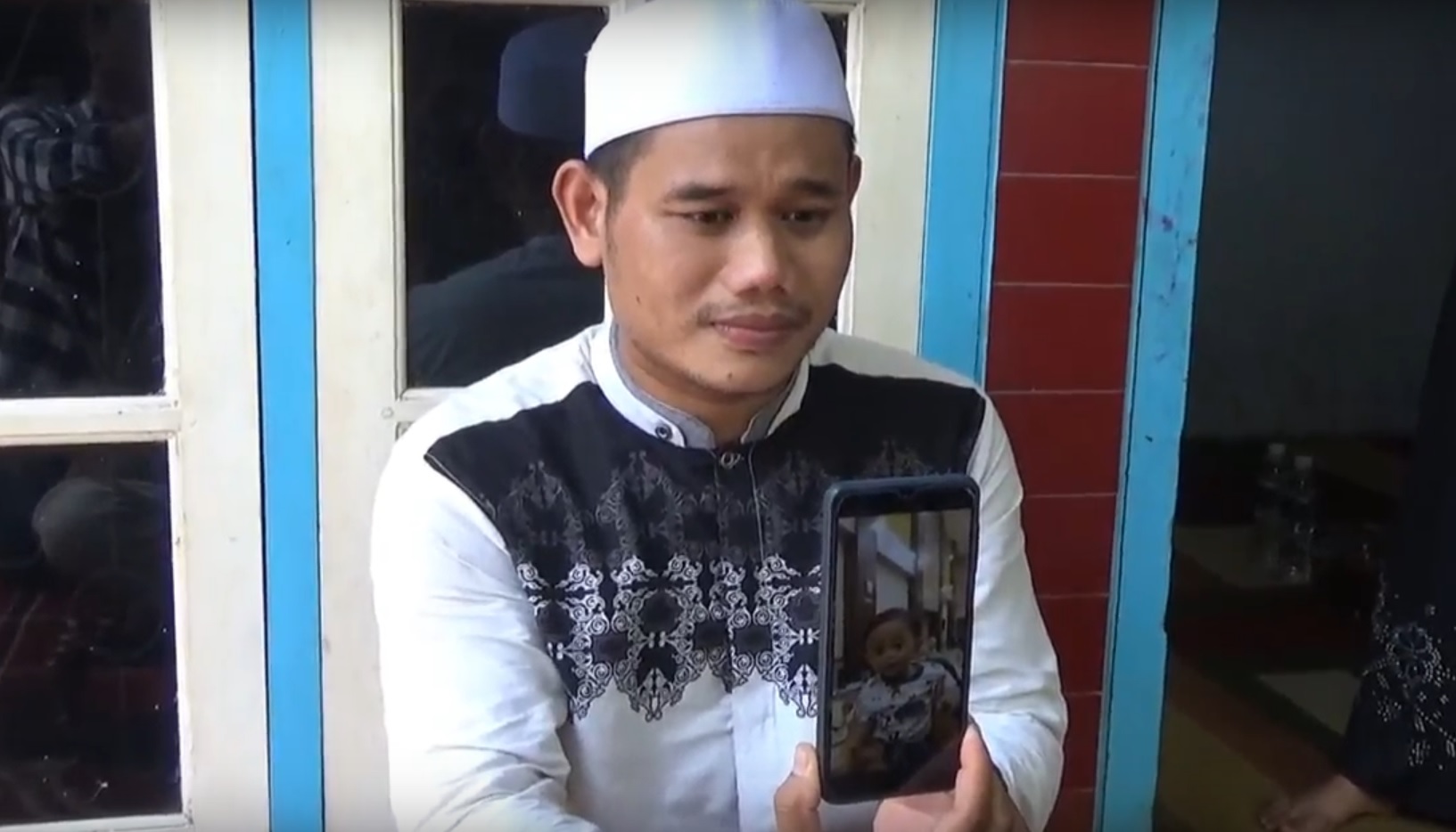 Sufian menunjukkan foto anaknya yang meninggal setelah divonis gagal ginjal akut (Foto / Metro TV)