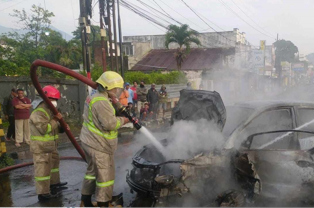 Petugas pemadam kebakaran mencoba memadamkan mobil yang terbakar (Foto / Istimewa)