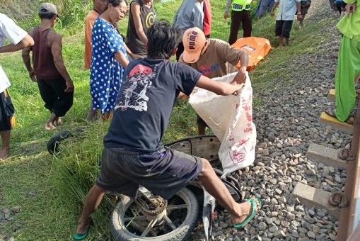 Polisi dibantu warga mengevakuasi motor milik korban yang hancur dihantam kereta api  (Foto / Istimewa)