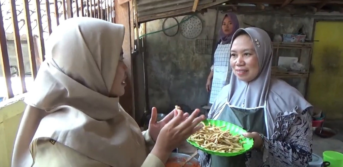 Sofiatul Husnah saat meminta pembeli mencicipi stik duri bandeng buatannya (Foto / Metro Tv)