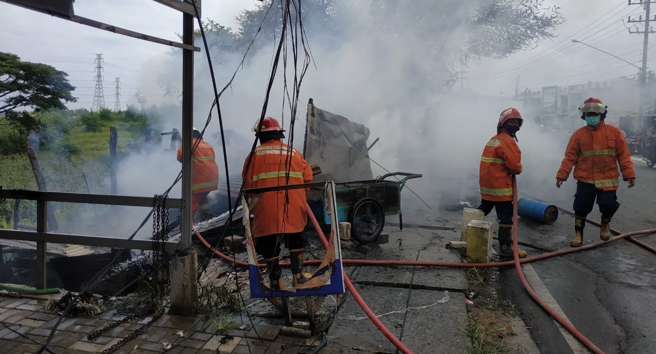 Petugas memadamkan api di kios yang terbakar (Foto / Clicks.id)