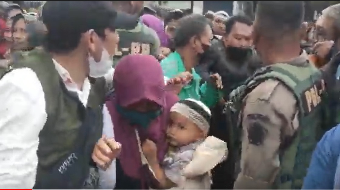 Petugas memberikan jalan kepada ibu dan anaknya yang terjepit antrian sembako/metrotv