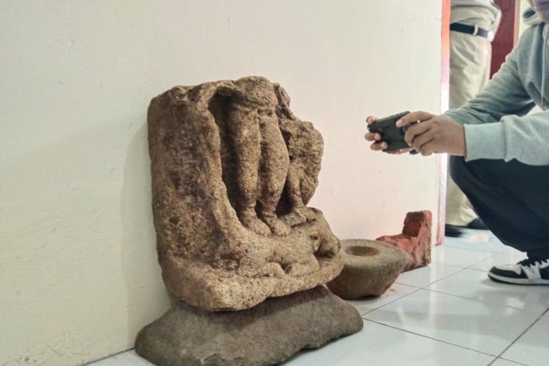 Perangkat desa memperhatikan potonga benda purbakala berbentuk arca yang ditemukan tertimbun tanah di dekat pondasi rumahnya di Desa Kamulan, Trenggalek, Senin (15/5/2023) (ANTARA/HO - Foto warga)