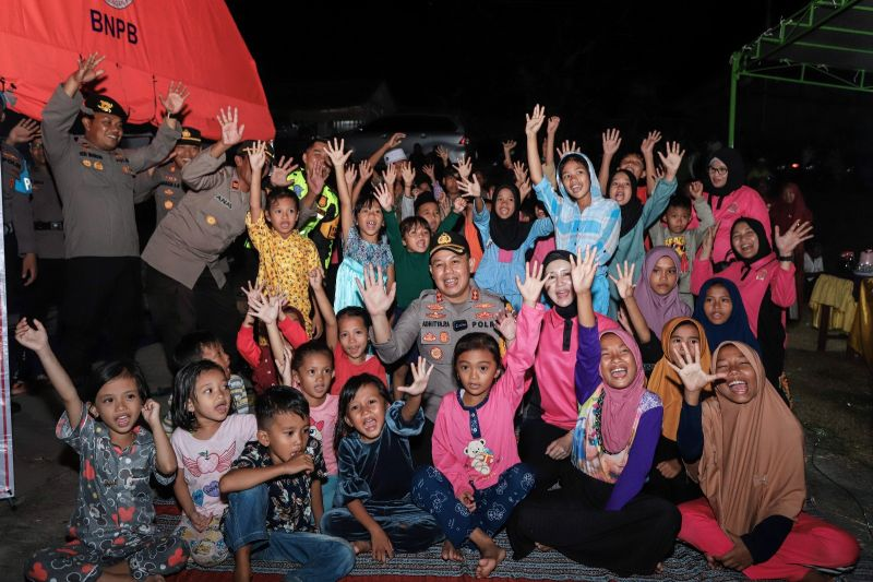 Kapolres Gresik AKBP Adhitya Panji Anom (tengah) foto bersama anak-anak terdampak bencana gempa di Desa Suwaru, Kecamatan Sangkapura, Pulau Bawean, Gresik, Senin (25/3/2024) malam. ANTARA/Rizal Hanafi.