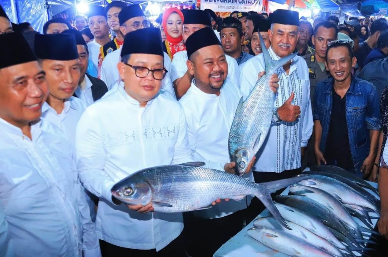Pj Gubernur Jawa Timur, Adhy Karyono dengan Bupati Gresik, Fandi Akhmad Yani memegang ikan bandeng dalam tradisi lelang bandeng di Kabupaten Gresik pada Senin (8/4/2024) malam. (ANTARA/HO-Biro Adpim Jatim)