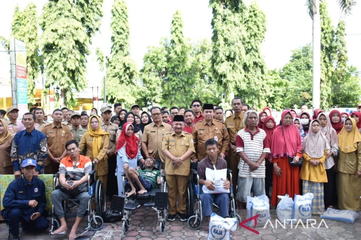 Bupati Situbondo, Karna Suswandi (tengah), foto bersama kaum disabilitas dan lansia penerima bantuan setelah memberikan bantuan kursi roda dan sembako. (ANTARA/HO-Humas Pemkab Situbondo)